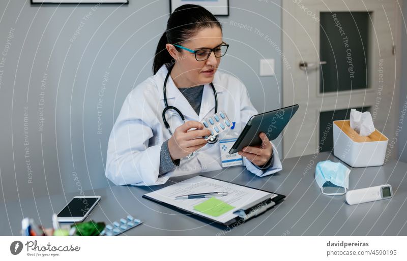 Ärztin liest Beipackzettel eines Medikaments auf einer Tablette Arzt Frau lesen Prospekt Pillen Behandlung Lernen auf der Suche nach Informationen online