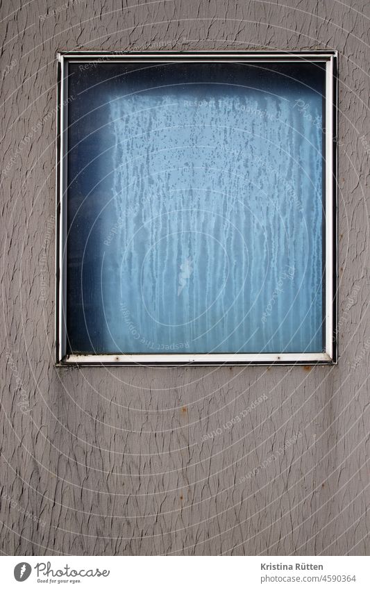 fenster und fassade in blau und grau mit regentropfen wassertropfen verregnet scheibe fesnterscheibe kondeswasser rollo viereck rahmen geometrisch muster form