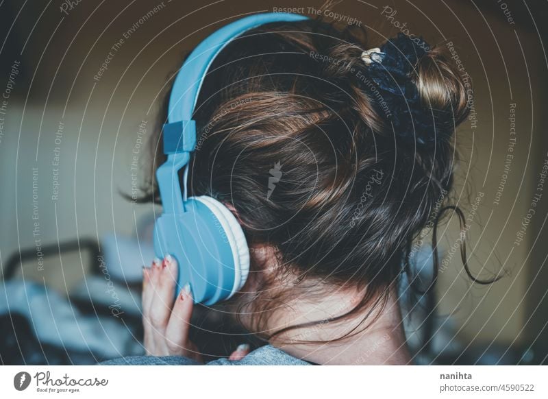Junge Frau hört Musik und trägt gemütliche Kleidung zuhören Kopfhörer Headset jung Jugend Teenager Musik hören Rücken Ansicht Brötchen Behaarung Frisur Komfort