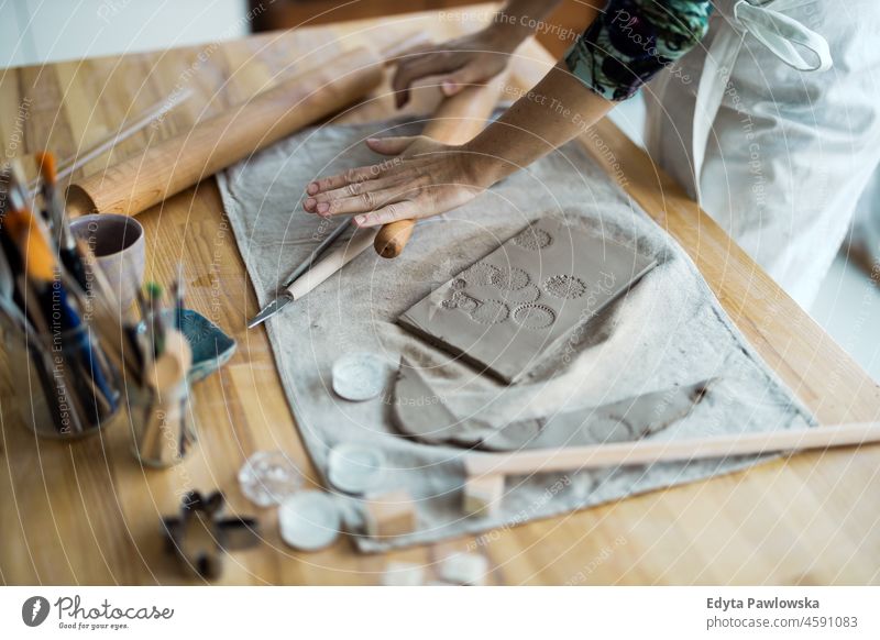 Nahaufnahme einer Kunsthandwerkerin bei der Arbeit an ihrer Töpferware in einer Werkstatt Hände abschließen Konzentration Geduld Topf traditionell Leiste