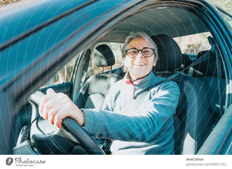 Porträt einer glücklich lächelnden älteren Frau, die das Autofahren lernt. Sicherheitsfahrt. Lernen neues Hobby, Gewohnheit und Fähigkeit für dieses neue Jahr. Ältere Person, die den Führerschein genehmigt.