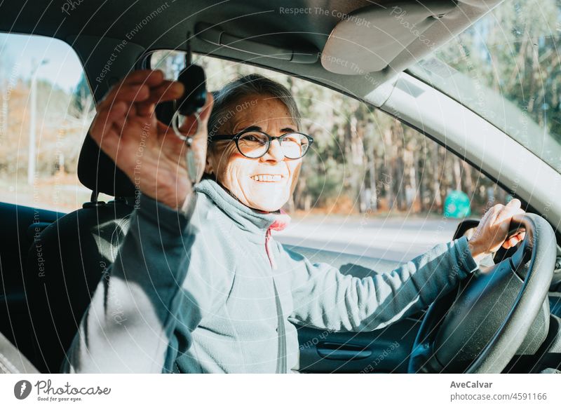 Porträt einer glücklichen lächelnden älteren Frau, die lernt, ein Auto zu fahren, indem sie den Autoschlüssel in die Kamera hält.Safety drive.Learning neues Hobby, Gewohnheit und Fähigkeit für dieses neue Jahr.Alte Person, die den Führerschein genehmigt