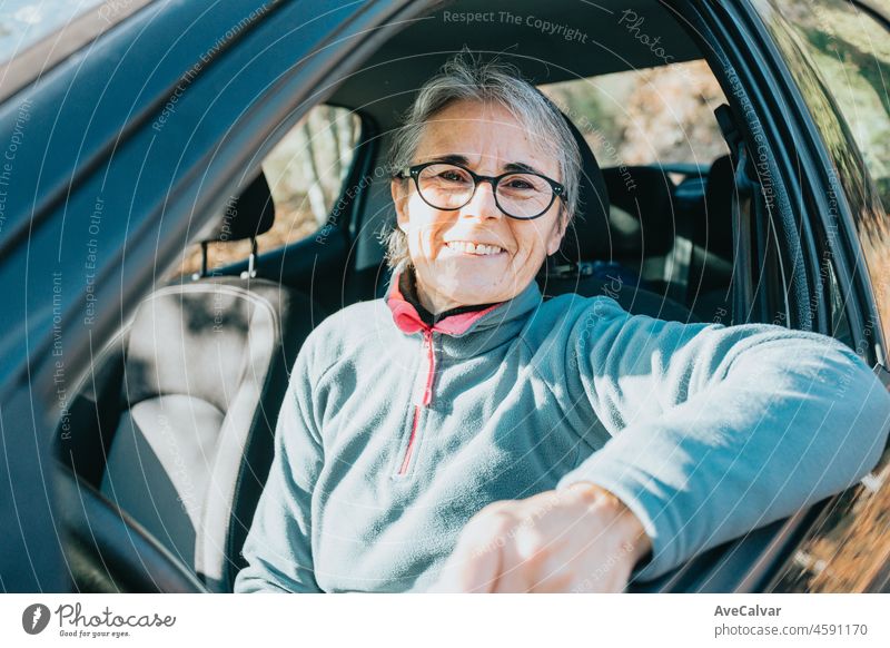 Porträt einer glücklich lächelnden älteren Frau, die das Autofahren lernt. Sicherheitsfahrt. Lernen neues Hobby, Gewohnheit und Fähigkeit für dieses neue Jahr. Ältere Person, die den Führerschein genehmigt.