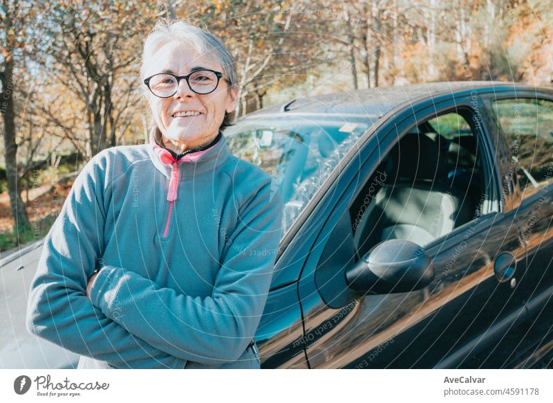 Porträt einer glücklich lächelnden älteren Frau vor dem Auto, die das Autofahren lernt. Sicherheitsfahrt. Lernen neues Hobby, Gewohnheit und Fähigkeit für dieses neue Jahr. Ältere Person, die den Führerschein genehmigt.