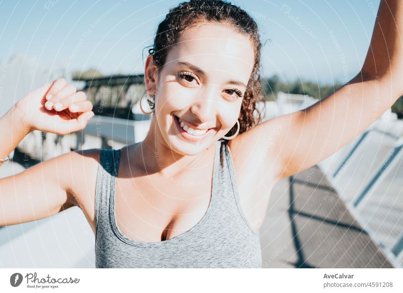 Afrikanische Sportlerin steht und feiert den Abschluss einer Übung und lächelt in die Kamera urbanes Sportszenario. Sonnenuntergang Zeit. Schönheit gesunde arabische Frau. Sport Klamotten, neue Gewohnheiten für ein neues Jahr, Gewicht zu verlieren.