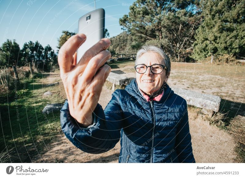 Eine ältere Frau macht ein Selfie beim Sport. Beginnt neue Gewohnheiten für das neue Jahr. Trekking und gesunder Lebensstil.Rentnerin Sport. Aging, Menschen, aktiven Lebensstil und Gesundheit Konzept