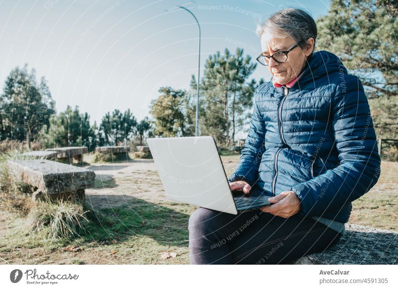 Eine ältere alte Frau mit Laptop im Freien Internet kopieren. Beginnt neue Gewohnheiten für das neue Jahr. Trekking und gesunden Lebensstil.Rentner Frau Sport. Aging, Menschen, aktiven Lebensstil und Gesundheit Konzept
