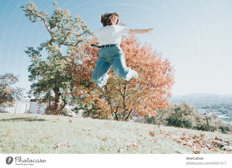 Outdoor-Porträt eines Teenagers kaukasischen kurvenreichen roten Kopf Mädchen springen auf dem Park mit Freiheit. Glück, jubelt und freudige Freiheit Menschen Konzept