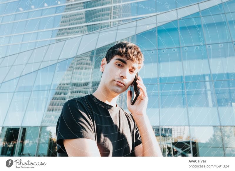 Junger Geschäftsmann auf dem Weg zur Arbeit, der vor einem Bürogebäude in der Stadt im Freien Anrufe entgegennimmt. Kopierraum Handy männlich Menschen Business