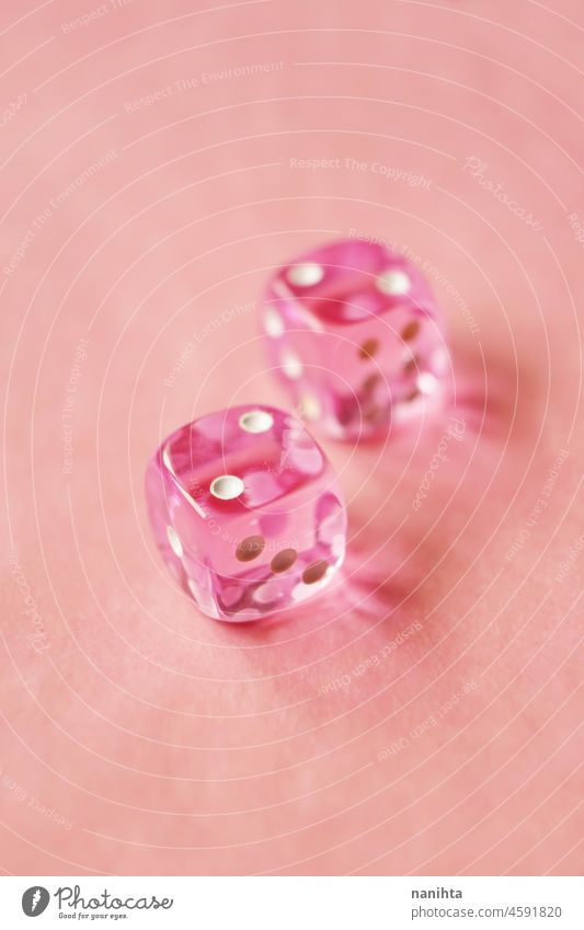 Eine lebendige monochromatische Makro mit Tiefenschärfe über zwei rosa Glas Glücksspiel Würfel mit zwei Unglückszahl zwei auf rosa Hintergrund. Spiel Wette