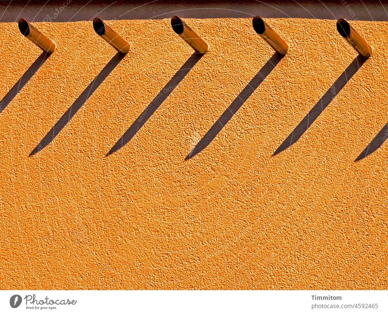 Teilansicht Fassade - orange Gebäude Putz Rohre Metall Licht Schatten Sonnenlicht Menschenleer Architektur Farbfoto Linien