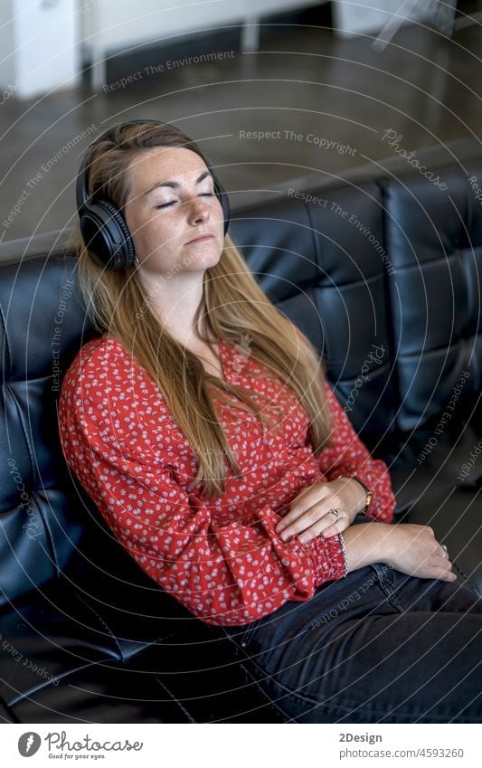 Frau zu Hause auf der Couch sitzend mit Kopfhörern Sitzen Sofa hören Musik Erholung Lifestyle im Innenbereich Wohnzimmer Textfreiraum bequem zuhören