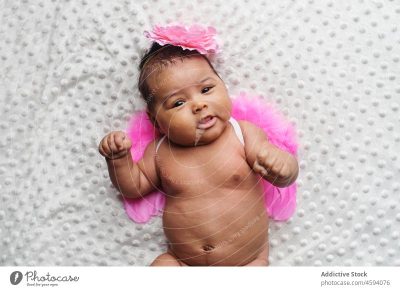 Niedliches ethnisches Baby mit Engelsflügeln und Stirnband Mädchen Säugling Flügel Säuglingsalter unverhüllt sanft unschuldig niedlich Kindheit wenig neugeboren