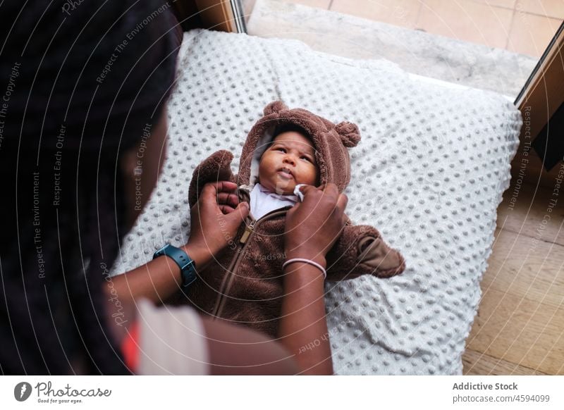 Schwarze Mutter zieht kleines Baby in Windeln an angezogen Body neugeboren Pflege Säuglingsalter Mutterschaft mütterlich Liebe Frau Kind wenig Eltern Sofa Lügen