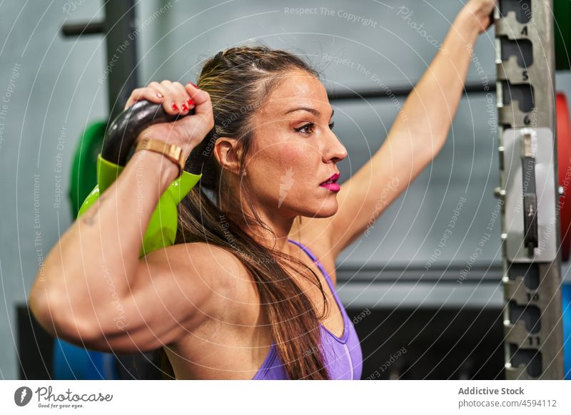 Fitte hispanische Sportlerin bei Kniebeugen mit der Kettlebell Training Übung Fitnessstudio passen muskulös stark Frau ethnisch Athlet physisch Sportbekleidung
