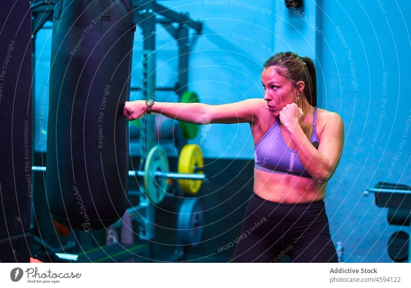 Starke hispanische Sportlerin trainiert mit Boxsack Boxer Bowle Tasche Training stark Boxsport Fitnessstudio Übung Frau ethnisch neonfarbig rosa Licht dunkel