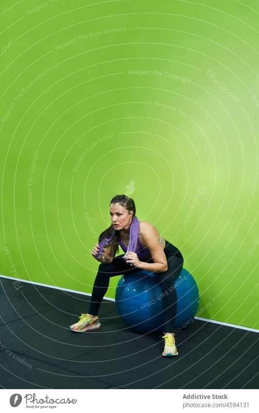 Ethnische Sportlerin sitzt auf einem Fitnessball müde Schweiß Fitnessstudio Pause pausieren Passform-Ball Athlet überdrüssig Handtuch Frau ethnisch hispanisch
