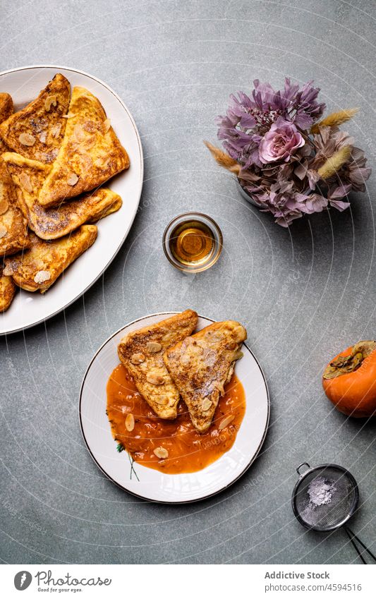 Teller mit französischen Toasts neben Kakis auf grauem Tisch Liebling lecker Glas Frühstück Lebensmittel Dessert süß Portion Zuprosten Persimone Ernährung