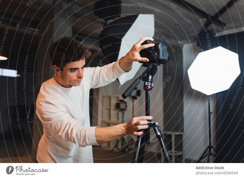 Mann stellt Fotokamera auf Stativ in Studio Fotograf Fotoapparat Fotosession professionell Fotografie fotografieren Linse Gerät Einstellung männlich Atelier