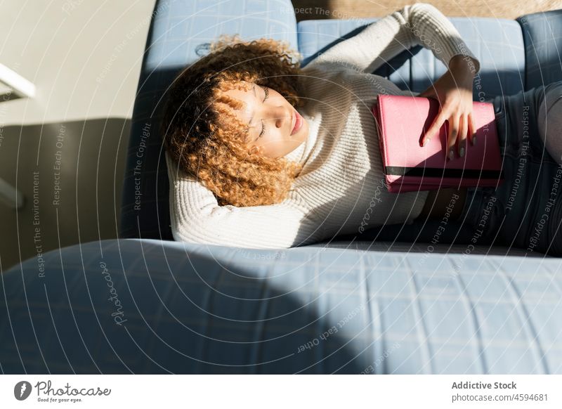 Schwarze Dame schlafend auf Sofa mit Tablette Frau Augen geschlossen Liege Schlummer Komfort ruhen sich[Akk] entspannen Mittagsschlaf Kälte ethnisch Apparatur