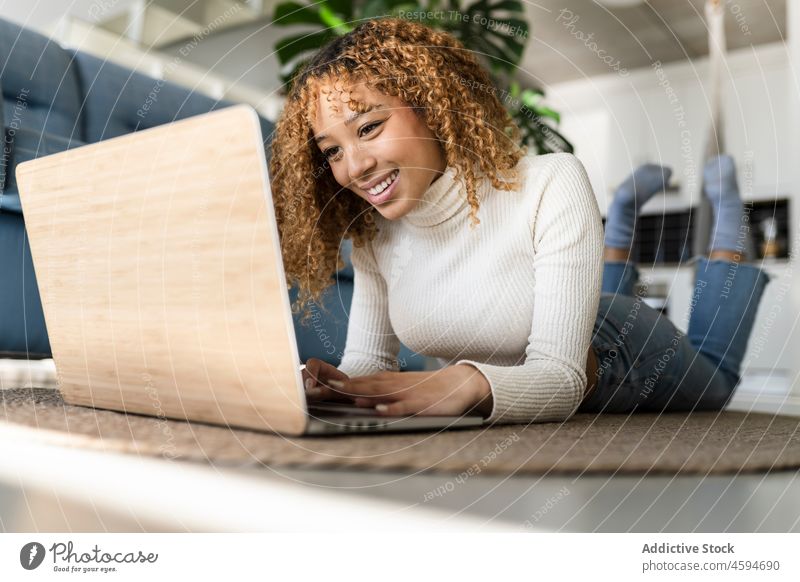 Fröhliche schwarze Frau benutzt Laptop zu Hause Tippen benutzend Lächeln unabhängig Freude freiberuflich Stock Arbeit Lügen ethnisch Dame heiter Apparatur
