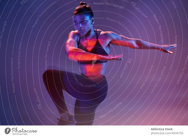 Starke Frau beim Training im Studio Sportlerin Übung Wellness neonfarbig passen Energie purpur Sportbekleidung jung Athlet schlank leuchten dunkel üben