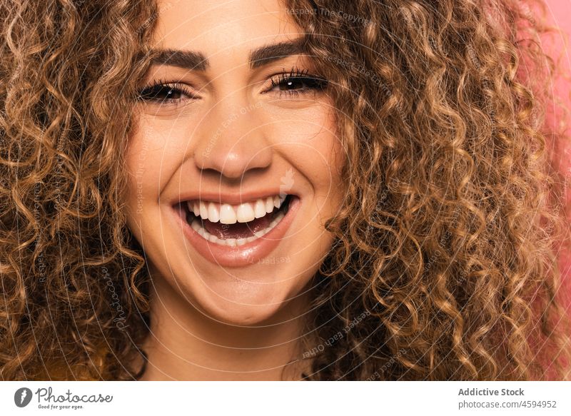 Lächelnde Frau mit lockigem Haar Glück heiter krause Haare positiv Optimist Freude Porträt froh Vorschein jung Zahnfarbenes Lächeln Menschliches Gesicht