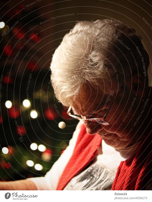 Schwiegermama sitzt am Esstisch, neben dem Weihnachtsbaum, und schaut nach unten Schwiegermutter Mutter oma Uroma Urgroßmutter Großmutter Blick Blick nach unten