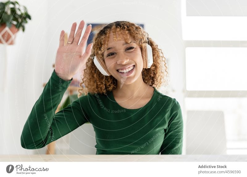 Positiv lächelnde ethnische Frau, die ein Grußzeichen zeigt Videoanruf Hallo gestikulieren zeigen manifestieren heiter salutieren positiv Glück Zeichen Symbol