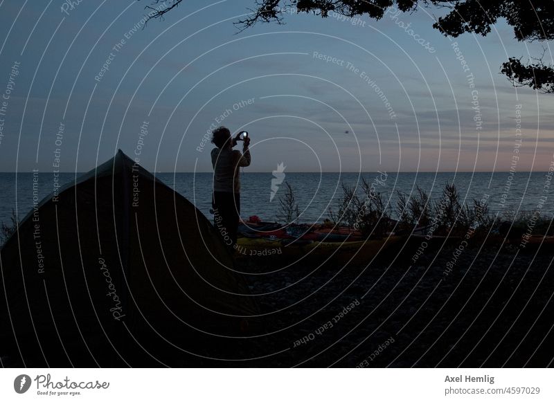 Bevor sie am Ostseestrand übernachtet fotografiert sie noch den Sonnenuntergang. Kanu Kanutour Kanufahren Kanusport Kanuwandern Sport Abend Paddeln Wind