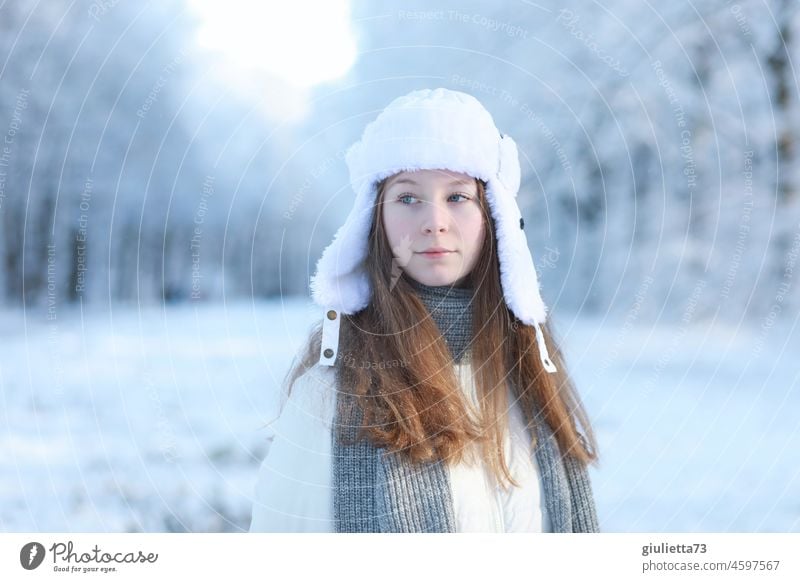 Winterliches Porträt eines langhaarigen Teenager Mädchens mit russischer Uschanka-Mütze im verschneiten Park Jugendliche 13-18 Jahre Junge Frau feminin