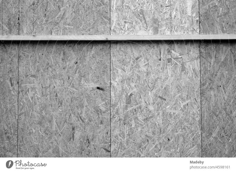 Improvisierte Holzverkleidung aus Spanplatten mit Querleiste in der Altstadt von Steihude am Steinhuder Meer bei Wunstorf im Landkreis Hannover, fotografiert in neorealistischem Schwarzweiß