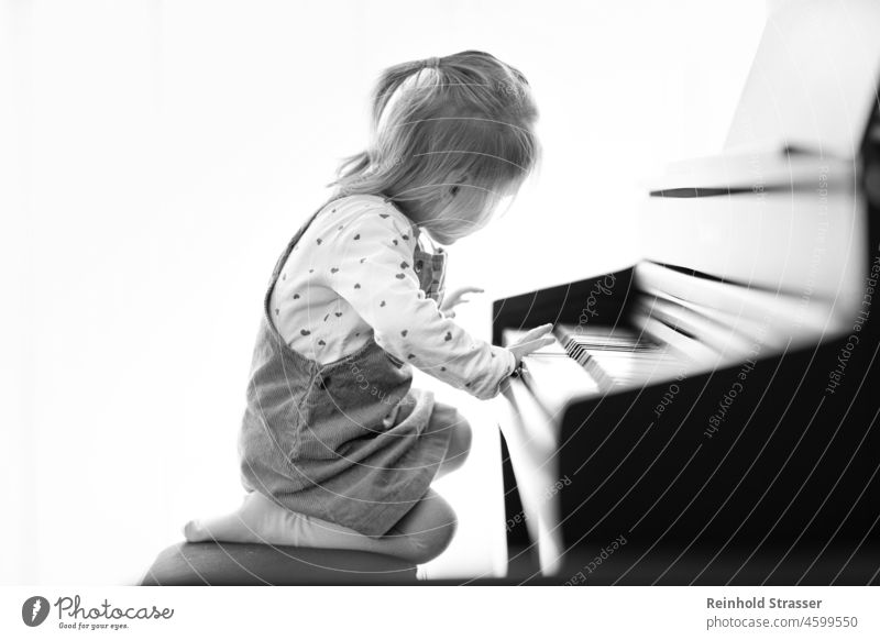 Mädchen am Klavier Kind Kleinkind Klavier spielen piano Pianotastatur Musik Musikinstrument musizieren Spielen lernen Leidenschaft faszinierend interessiert