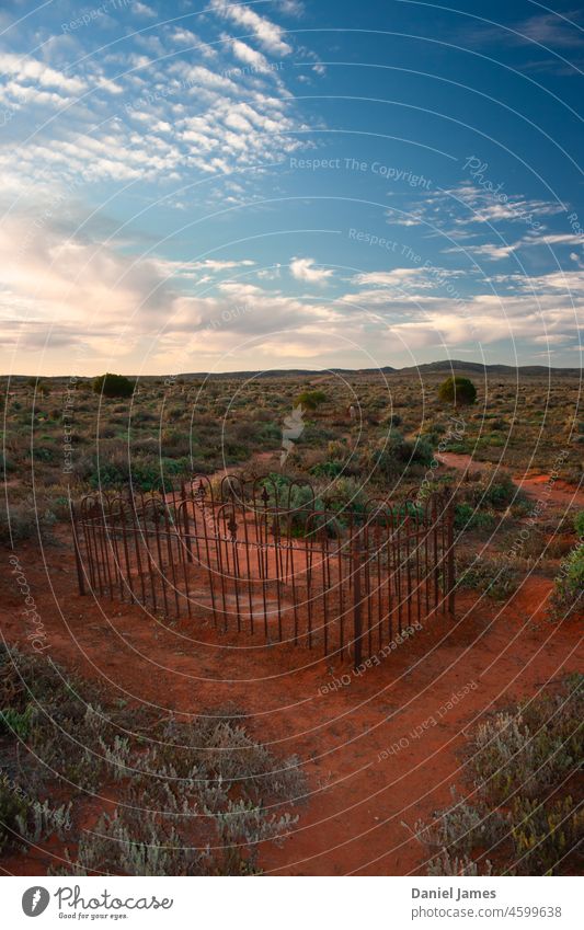 Verlassener Friedhof in der Wüste. Grab wüst Menschenleer Outback verfallen Zaun rustikal Rust Landschaft Vegetation Himmel Wolken einsam allein historisch