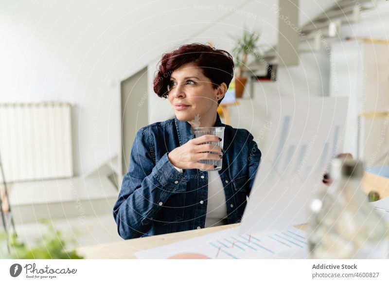 Frau mit Wasserglas, die Diagramme untersucht Tabelle freiberuflich analysieren Arbeit Arbeitsplatz Projekt Schriftstück Daten Glas Durst Grafische Darstellung