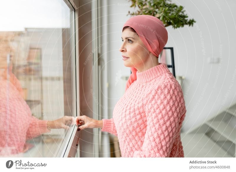 Frau mit Kopftuch schaut aus dem Fenster Krebs Mode Chemotherapie Onkologie beobachten nachdenklich krank Krankheit verträumt kämpfen Glaube Hoffnung Überleben