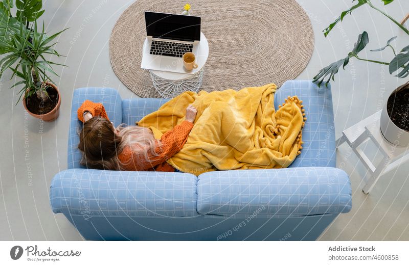 Anonyme Frau auf der Couch, die ein Video auf ihrem Laptop anschaut Liege gemütlich Komfort Internet Wochenende Freizeit ruhen zuschauen Film Plaid Sofa Gerät