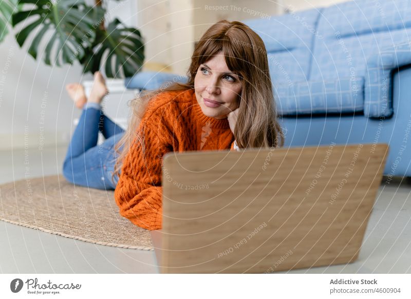 Frau mit Laptop auf dem Boden Tippen Internet Freizeit Browsen heimisch Appartement online Zeitvertreib Sofa Gerät Netbook Apparatur interessant heimwärts