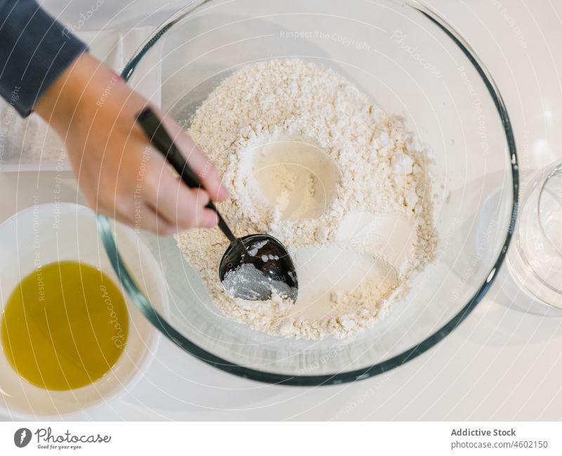 Ein Kleinkind, das Mehl mit einem Löffel zerdrückt Kind Koch Bestandteil kulinarisch Gebäck vorbereiten Bäckerei eingießen Teig Schalen & Schüsseln Küche Hand