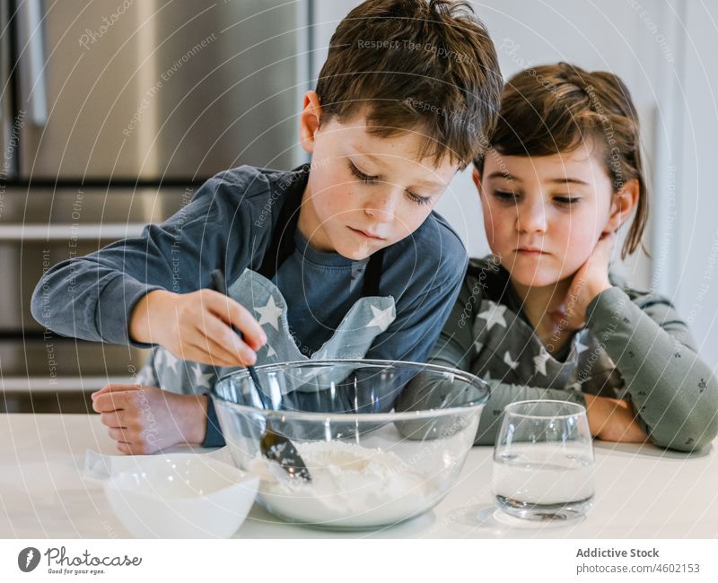 Fröhliche Geschwister, die in der Küche gemeinsam Teig anrühren Geschwisterkind Koch Junge Mädchen mischen kulinarisch Mehl Teigwaren Liebe Kinder Zusammensein