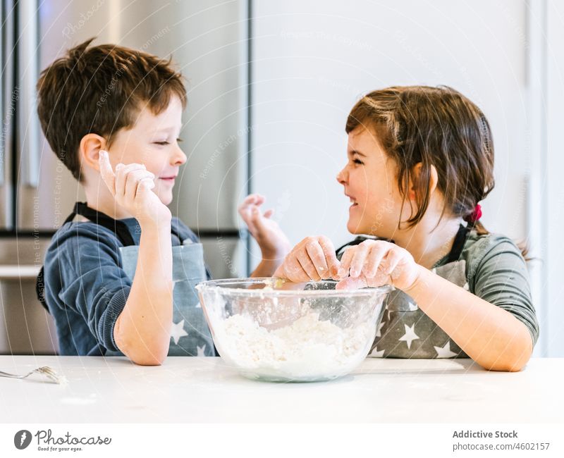 Kinder mischen gemeinsam Teig in einer Schüssel Geschwisterkind Küche Koch kulinarisch Mehl Teigwaren Zusammensein Küchengeräte Bruder Schwester kneten Hand