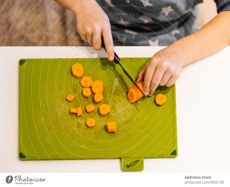 Anonymer Junge schneidet Karotte in der Küche Koch Möhre Kind geschnitten kulinarisch zu Hause Lebensmittel Helfer Scheibe vorbereiten Küchengeräte Prozess