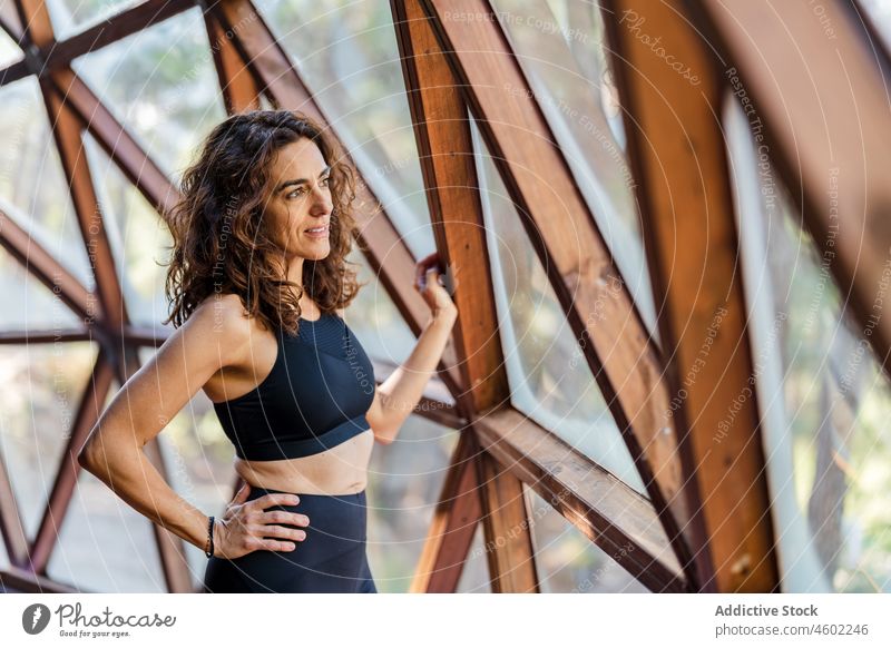Fitte Frau schaut aus dem Fenster sportlich Sportbekleidung Yoga Wohlbefinden Gesunder Lebensstil beobachten Hobby Wellness Atelier passen schlank Rahmen