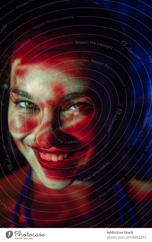 Lächelnde Frau im Dunkeln mit Lichtprojektion leuchten Projektor Porträt glühen Konzept Starrer Blick Deckblatt rot Abenddämmerung jung Sinnestäuschung Nacht