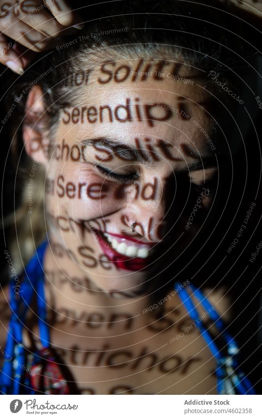 Fröhliche Frau mit Aufschrift im Gesicht Projektor Porträt Einsamkeit serendipity leuchten Konzept Deckblatt Wort Text Zahnfarbenes Lächeln Einfluss jung