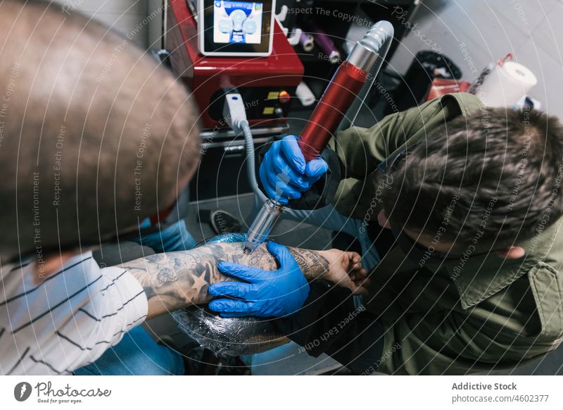 Meister macht Laser-Tätowierung auf der Hand eines Mannes Männer Tattoo Salon machen Klient professionell Arbeit Maschine männlich Konzentration Tusche Fokus