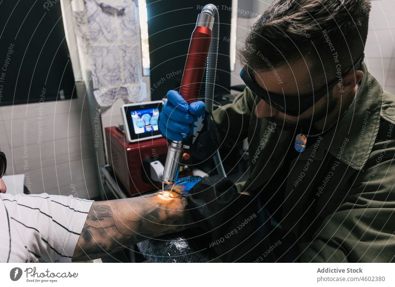 Meister macht Laser-Tätowierung auf der Hand eines Mannes Männer Tattoo Salon machen Klient professionell Arbeit Maschine männlich Konzentration Tusche Fokus