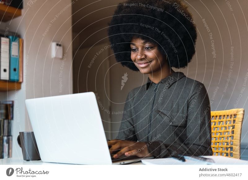 Fröhliche schwarze Frau tippt auf einem Laptop Arbeit Browsen online Tippen freiberuflich Arbeitsplatz abgelegen Internet modern Netbook Surfen heimwärts