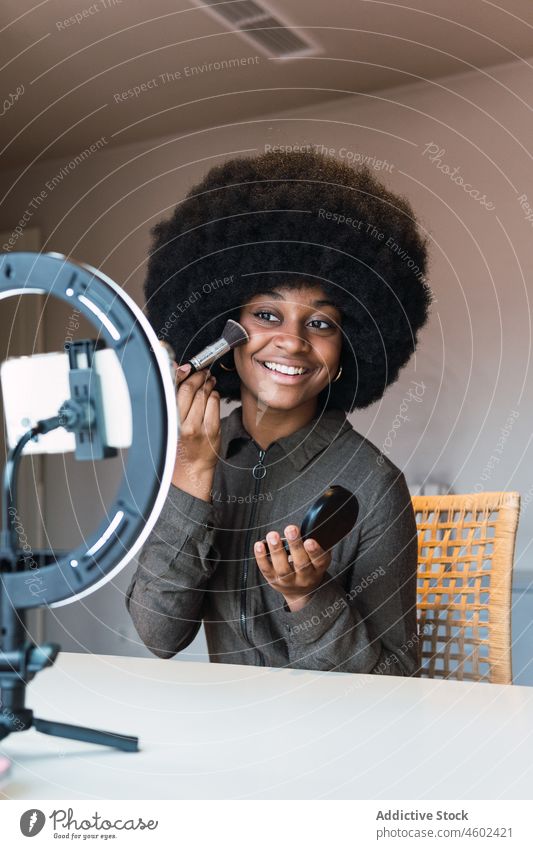Schwarze Frau nimmt Schönheitsvideo auf Make-up Tutorial Kosmetik vlog Smartphone Ringlampe Pulver Video Blog soziale Netzwerke online Afro-Look Aufzeichnen
