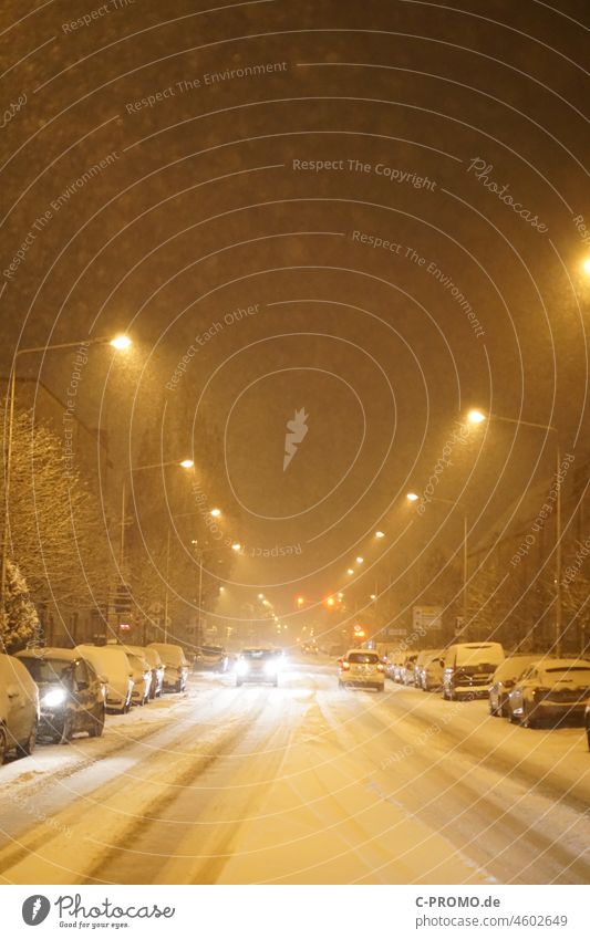 Wintereinbruch in Stadt Straße Fahrzeuge Laternen Licht Nacht schneebedeckt Scheinwerfer Winterreifen glätte Schneefall schneechaos